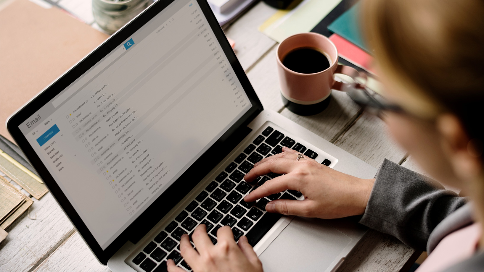 Das Bild zeigt eine Frau, die in einem Café ihre Mails checkt.