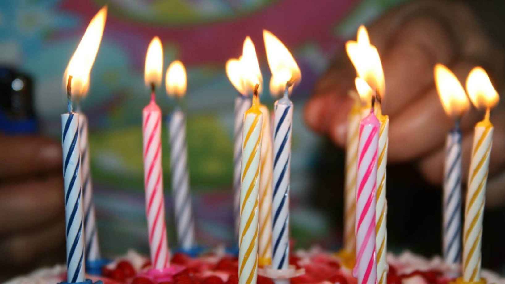 Das Bild zeigt einen Geburtstagskuchen mit brennenden Kerzen.