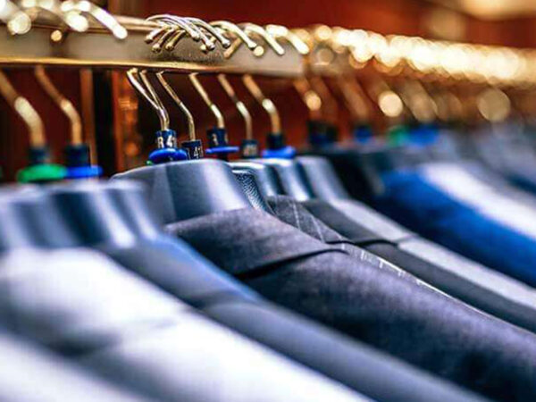 La photo montre une tringle à vêtements avec des vestes de costume.