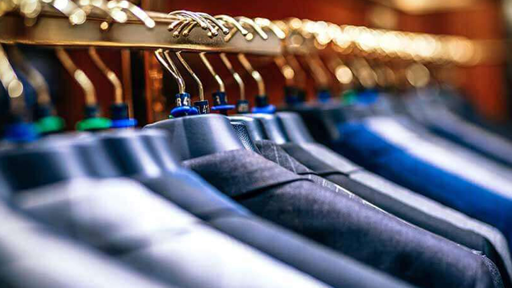 Das Bild zeigt eine Kleiderstange mit Anzug-Jackets.