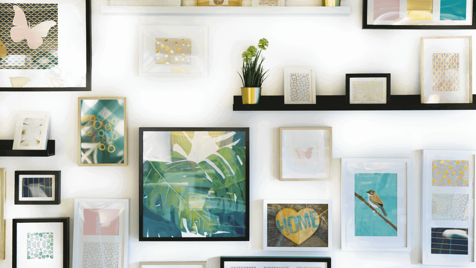 Das Bild zeigt eine Mit Bildern und Blumen dekorierte Wand. Es wirkt sehr stimmig.