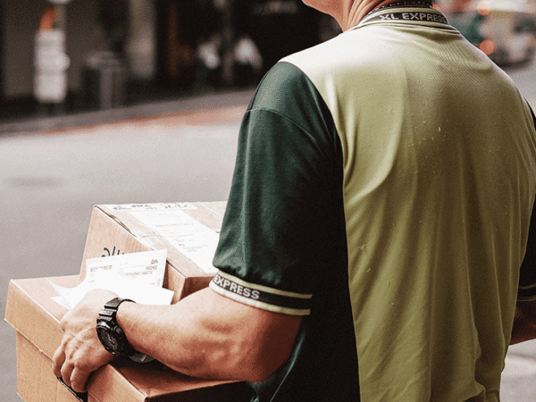 Das Bild zeigt eine Postboten, der dem Retourenprozess beiträgt und Pakete zurückbringt.