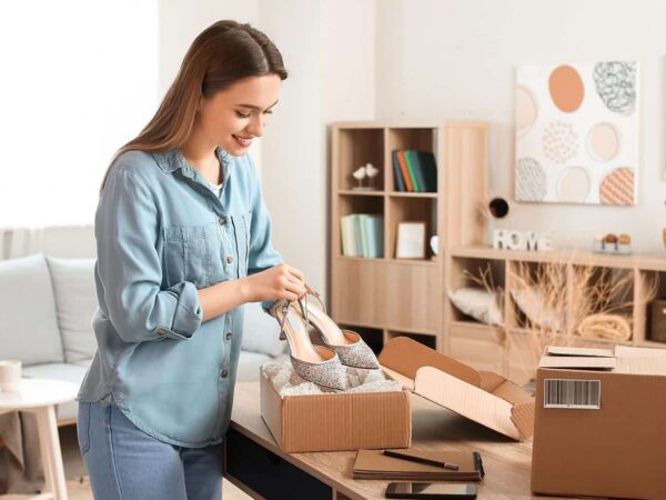 Eine Frau packt ein Paket mit Schuhen aus und lächelt zufrieden.