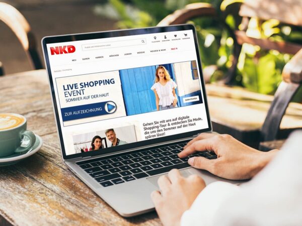 Eine Person vor einem Laptop, auf dem eine Content-Seite zu Live Shopping Events aufgerufen ist.