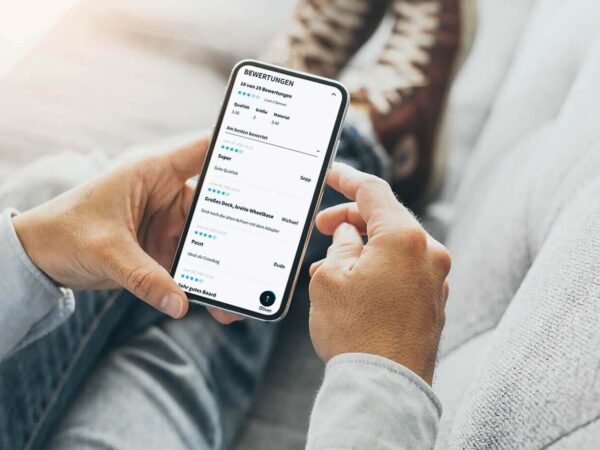 Eine Person hält ein Smartphone in der Hand, auf dem mehrere Produktbewertungen zu sehen sind.