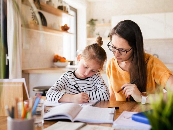 Eine Mutter schaut ihrem Kind beim Lernen über die Schulter.
