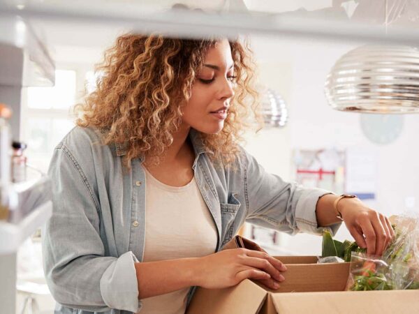 Eine Frau räumt Lebensmittel, die sie über den Online-Handel bestellt hat, in ihren Kühlschrank ein.