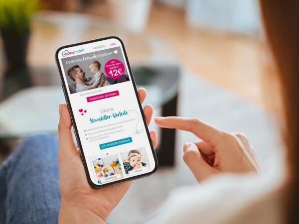 Eine Frau hält ein Smartphone in der Hand, auf der eine Win-Back-Mail als eine Maßnahme zur Kundenrückgewinnung zu sehen ist.