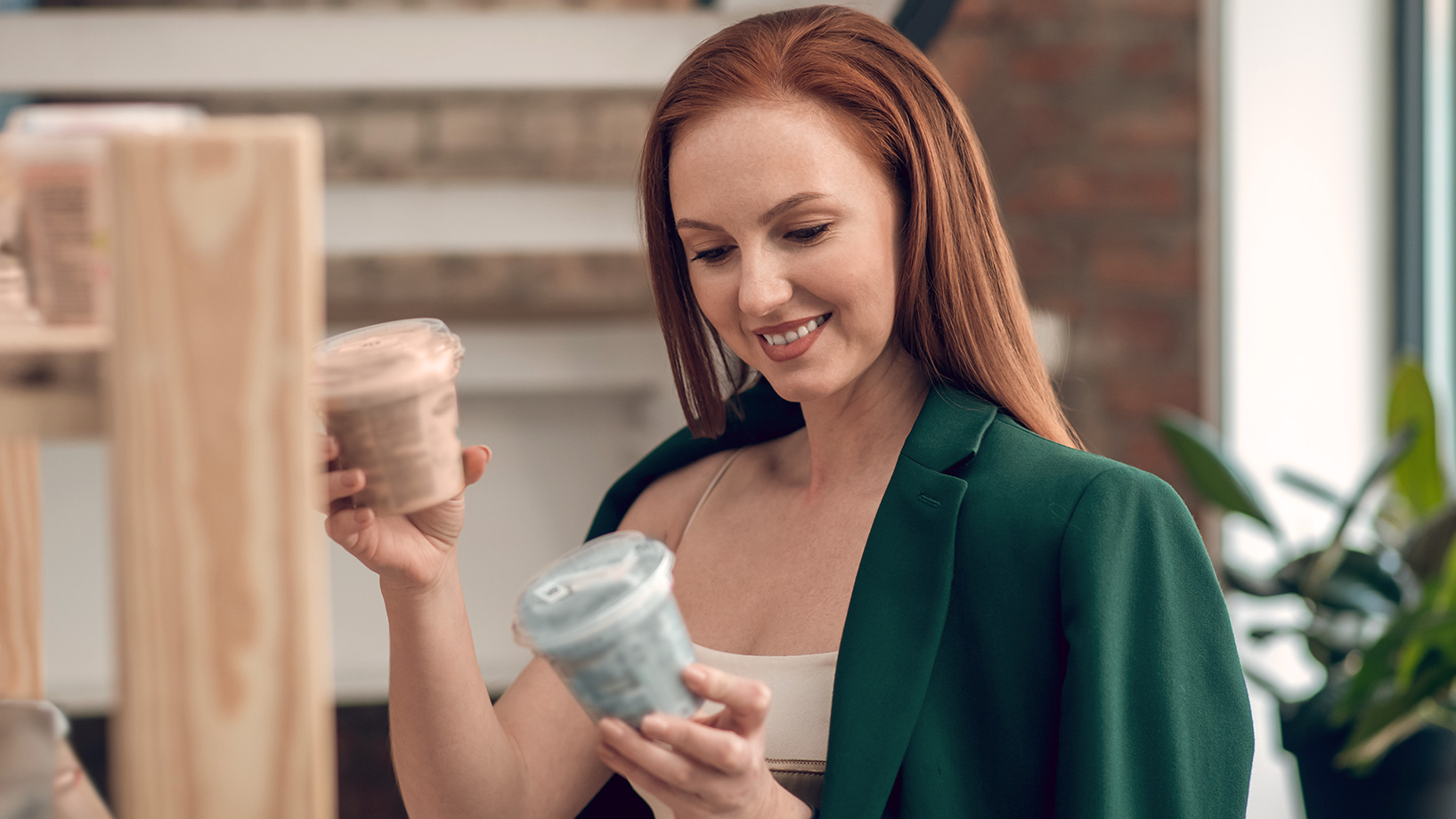 Eine Frau hält zwei Produkte in den Händen und studiert die Verpackung eines Artikels genauer – ähnlich wie beim Lesen einer Produktdetailseite im Online Shop.