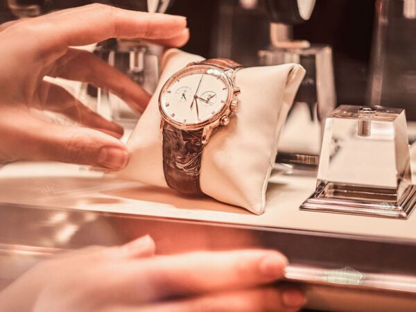 Hand platziert Uhr auf kleinem Präsentationskissen im Schaufenster als symbolische Darstellung von Onsite Merchandising.