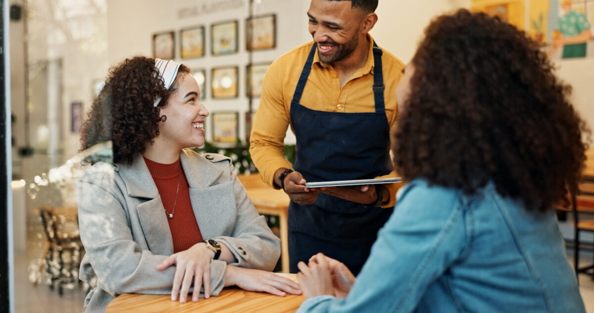 Mitarbeiter zeigt Kundinnen personalisierte Produktempfehlungen auf dem Tablet – Personalization Insights von Epoq