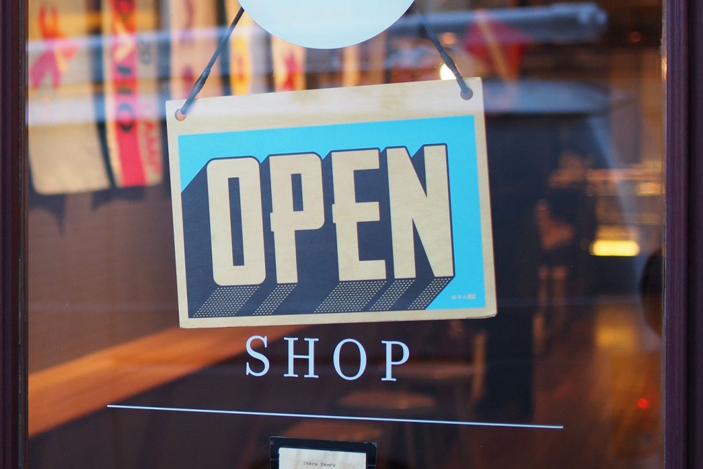 Im Schaufenster eines Shops hängt ein blaues Schild mit weißer Schrift, mit der Aufschrift "OPEN". Das Bild steht symbolisch für die Kunden, die bereits die Onsite-Suche nutzen.