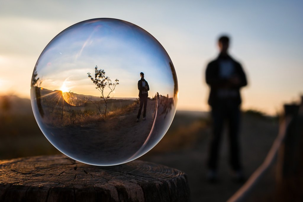 Eine Seifenblase zeigt eine Person die auf der Straße im Sonnenuntergang steht. Die Seifenblase symbolisiert die künstliche Intelligenz die auch in Online Shops für Recommendations eingesetzt wird.