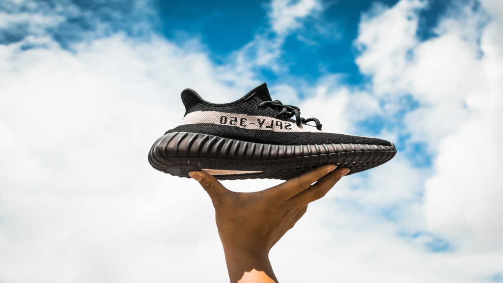 Eine Hand hält einen Sneaker in die Luft