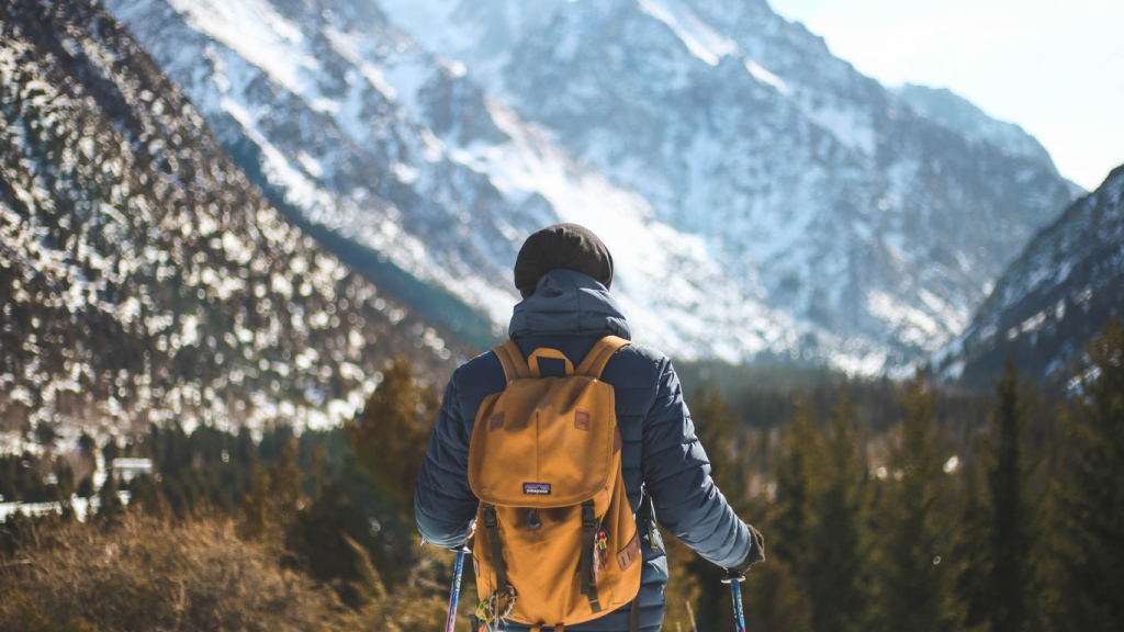 Ein Wanderer unterwegs in einem Gebirge mit Blick auf Berge