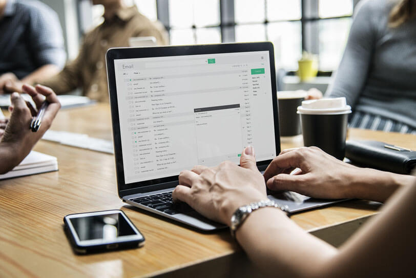 Eine Person sitzt vor einem Laptop auf dem ein E-Mail-Programm geöffnet ist und sieht sich verschiedene E-Mail-Kampagnen an.