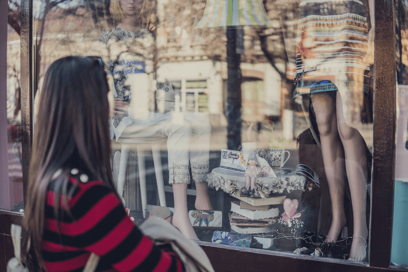 Das Bild zeigt eine Person, die vor einem Schaufenster steht – dieses steht im übertragenen Sinne für die Startseite des Online Shops, die optimal gestaltet werden sollte.
