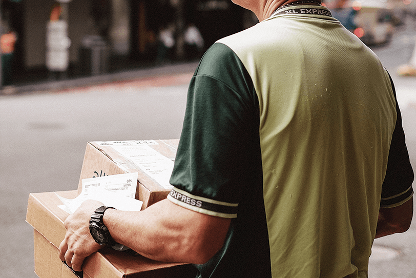 Das Bild zeigt eine Person mit Paketen in der Hand.
